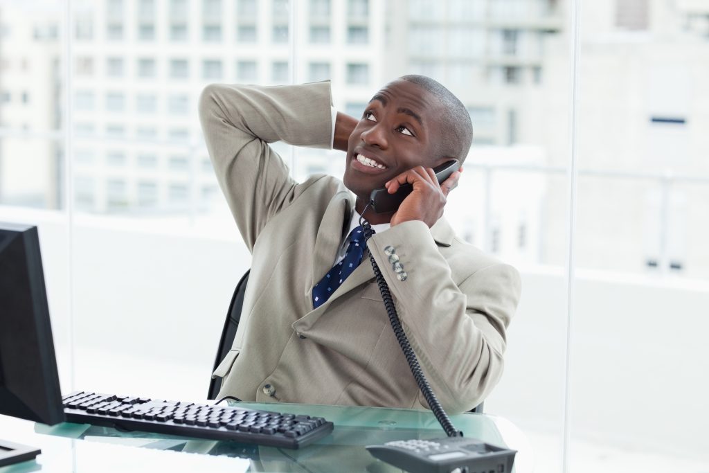 Smiling business man on the phone showing that he is enjoying what he hears in the on hold messaging - on hold marketing concept