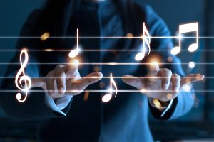 business mans hands playing glowing music staff hovering in front of him to represent the use of music in business