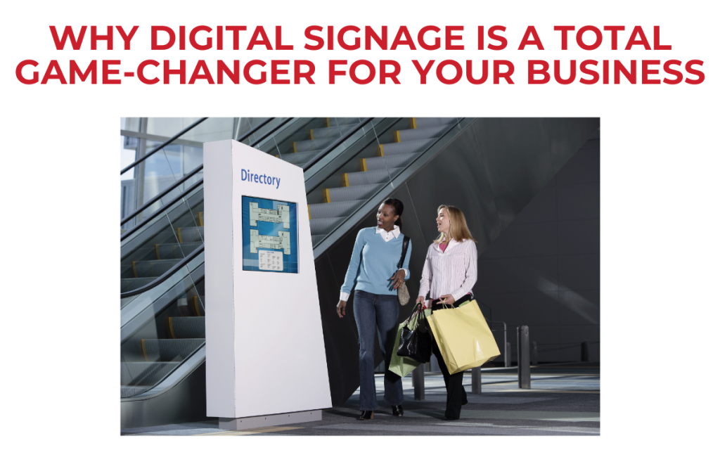 smiling women with shopping bags in retail mall checking out digital sign with mall directory displayed explaining what is on both floors next to escalator