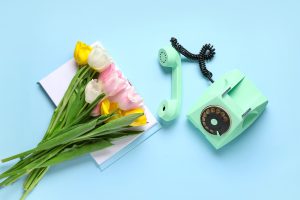 Landline phone off the hook next to bouquet of flowers from florist, showing the importance of on-hold music and messaging for a florist