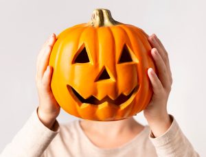 Woman holding decorative pumpkin instead of head over gray background