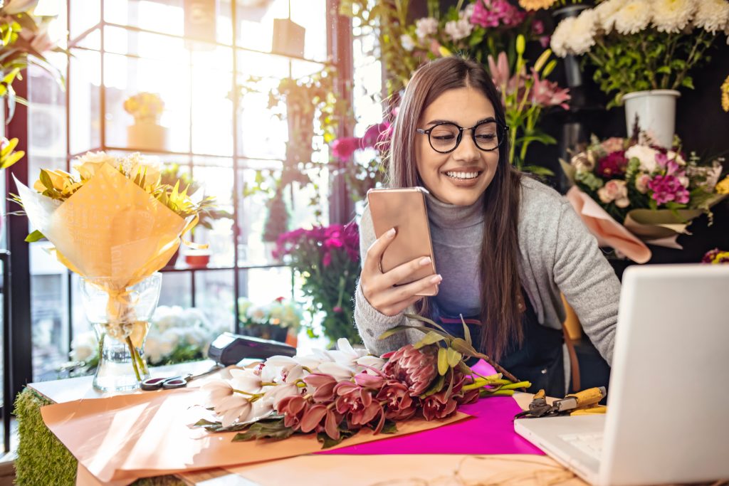 New Year’s resolutions aren't just for personal goals—they're also a powerful tool for businesses - smiling florist shop owner on phone and computer