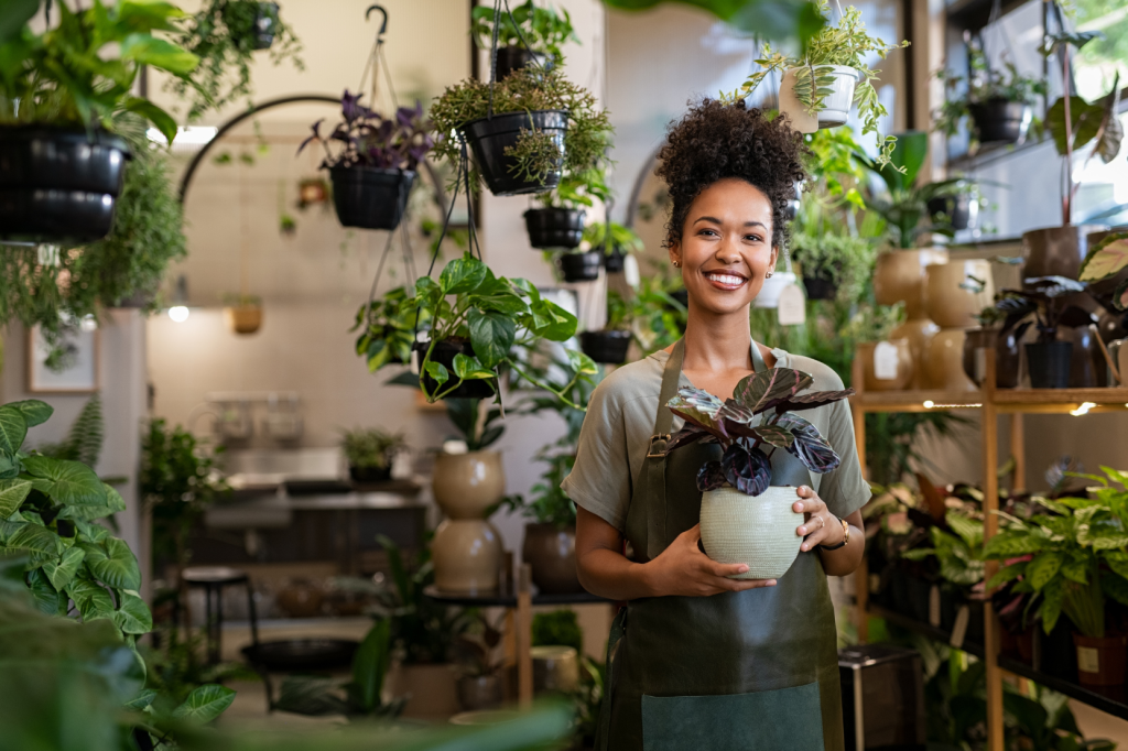 For businesses, resolutions are not just annual traditions but strategic tools essential for continuous improvement and growth - smiling happy business associate in plant shop holding pot and looking at the camera