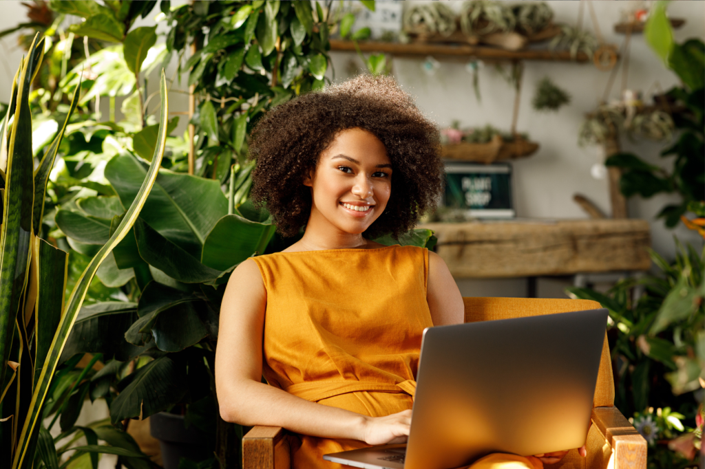 For businesses, this period of setting resolutions is crucial for aligning strategies with market dynamics and recalibrating company objectives for the upcoming year - smiling business owner sitting in plant shop on computer